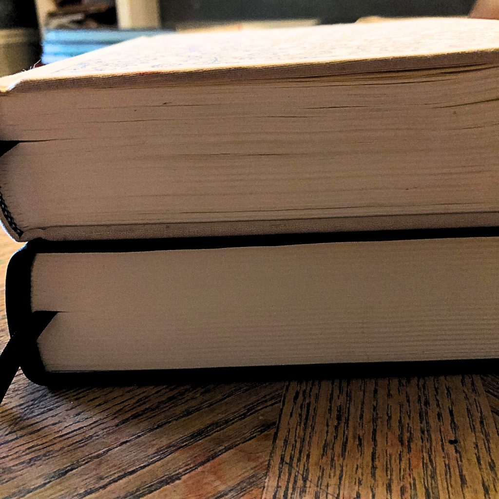 Picture of two stacked Bibles with the large print journaling Bible on the bottom and the regular print on top to show the difference in thickness between the two. 