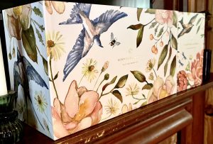 Two floral boxes sitting side by side on a wooden mantle. 